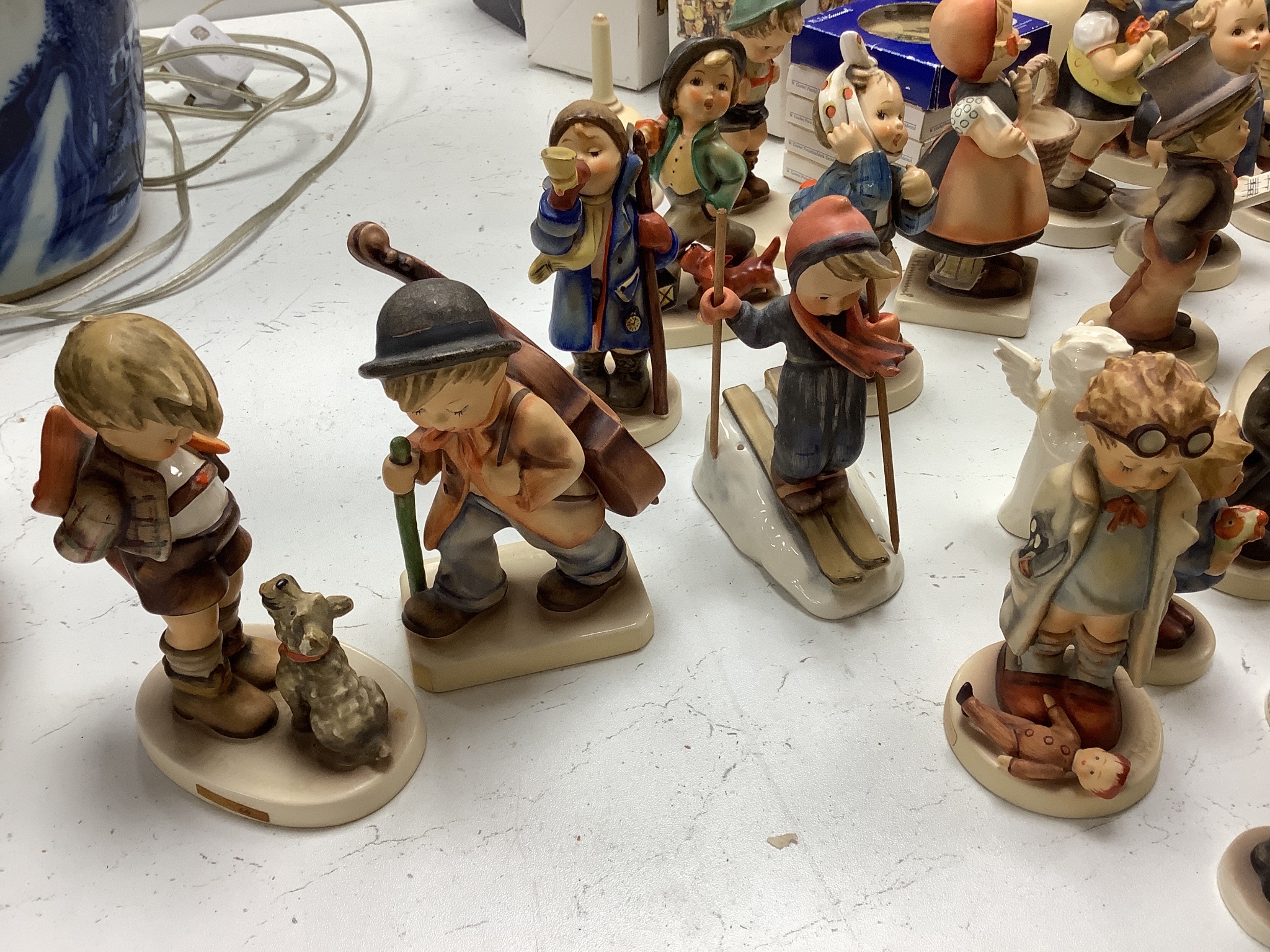 A large collection of Hummel pottery figures, approximately 70 including skier and two similar plaques, some with boxes.